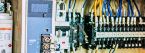 Close-up of a 24VDC DIN rail power supply, terminal blocks, and control wiring inside an industrial PLC panel