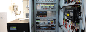 Open industrial control panel with PLCs and electrical components used to calculate enclosure heat dissipation and cooling requirements