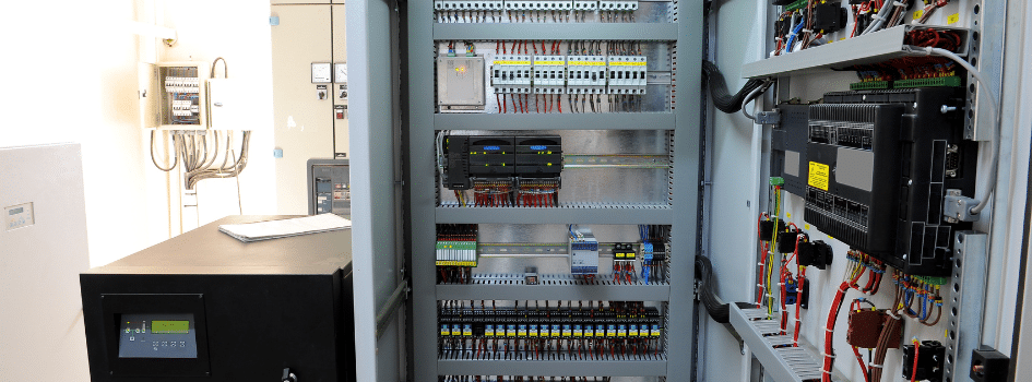 Open industrial control panel with PLCs and electrical components used to calculate enclosure heat dissipation and cooling requirements